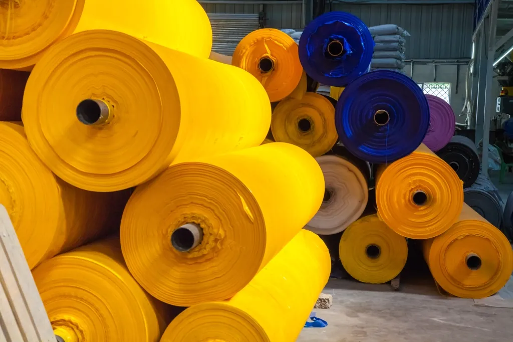 Stacked yellow and blue multilayer tarpaulin rolls